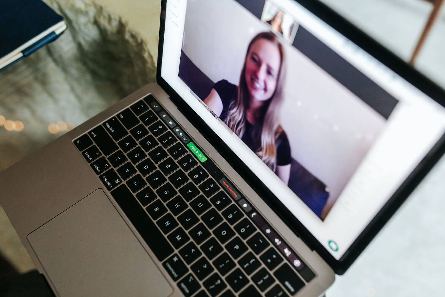 Dubsado for coaches. Image Description: Looking down on a laptop at an angle, the screen is open to Zoom and a blonde woman wearing a black top is smiling into the camera.