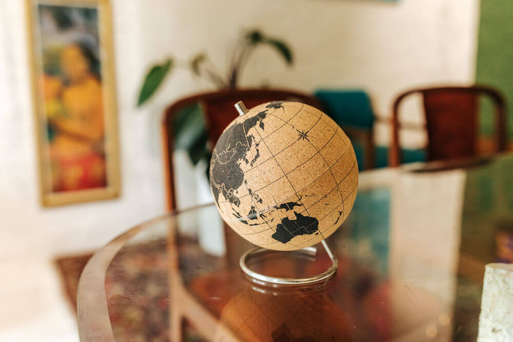 A corkboard globe sitting on a glass table